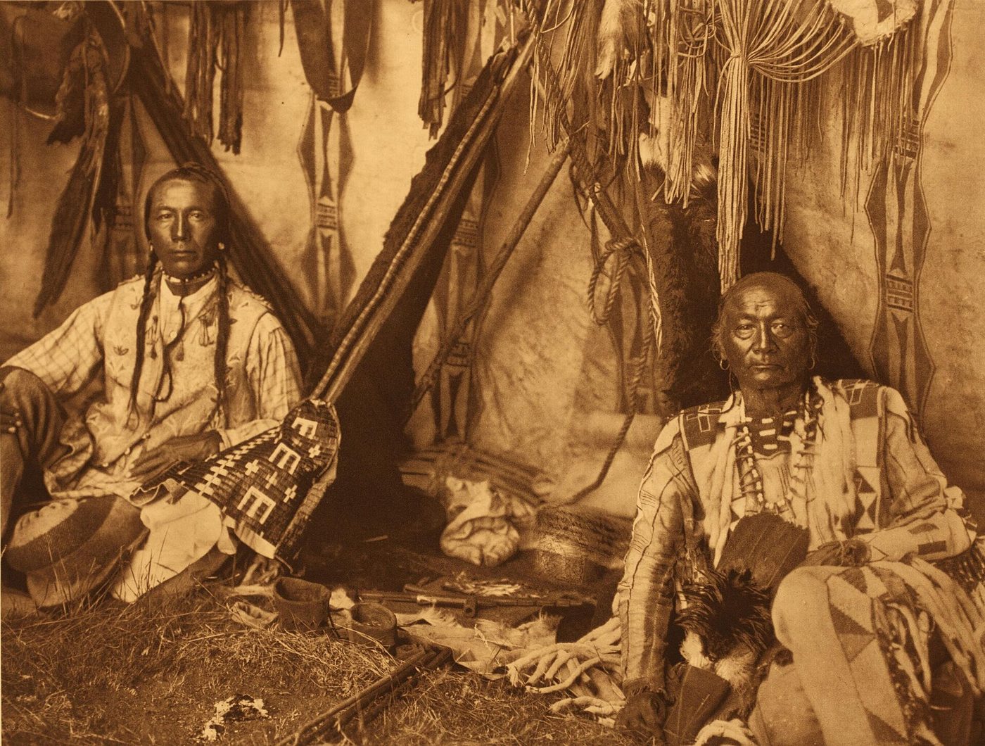 La misma escena en tono sepia publicada como fotograbado: los dos hombres en la misma postura, pero el espacio entre ellos muestra solo el suelo y las mantas