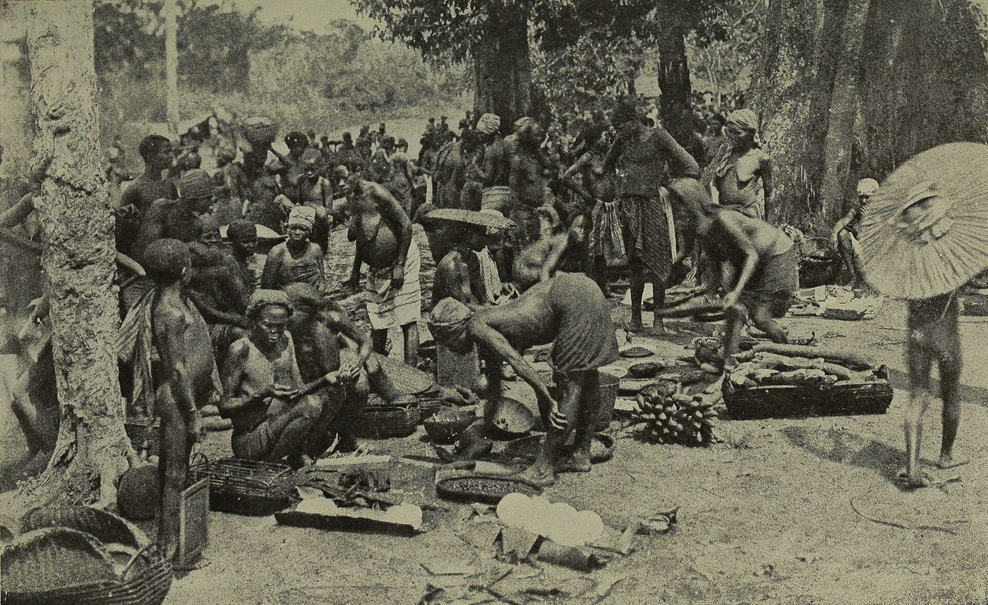 Fotografía de 1921 de un mercado africano al aire libre lleno de gente, con puestos y mercancías en el suelo