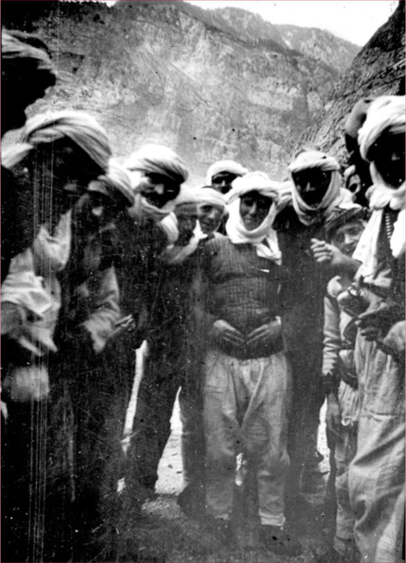 Fotografía de 1908 de un grupo de personas con gorros blancos reunidas en un exterior montañoso