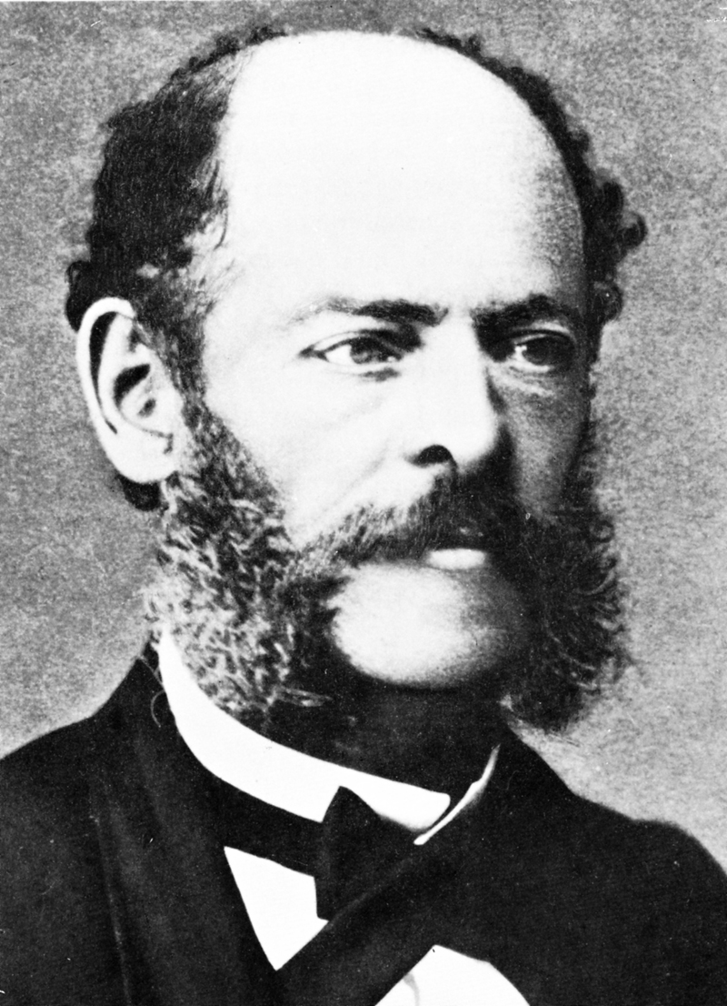 Retrato fotográfico del siglo XIX de un hombre de barba y entradas, con corbata de lazo y chaqueta oscura