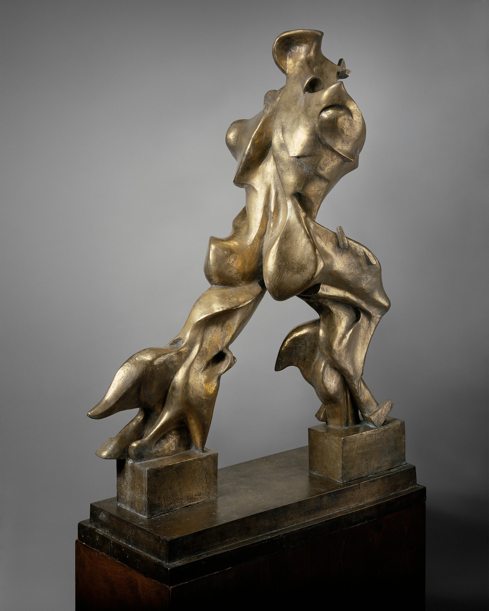 Escultura de bronce de una figura humana que avanza a grandes zancadas, con el cuerpo convertido en formas curvas y aerodinámicas que se despliegan hacia atrás