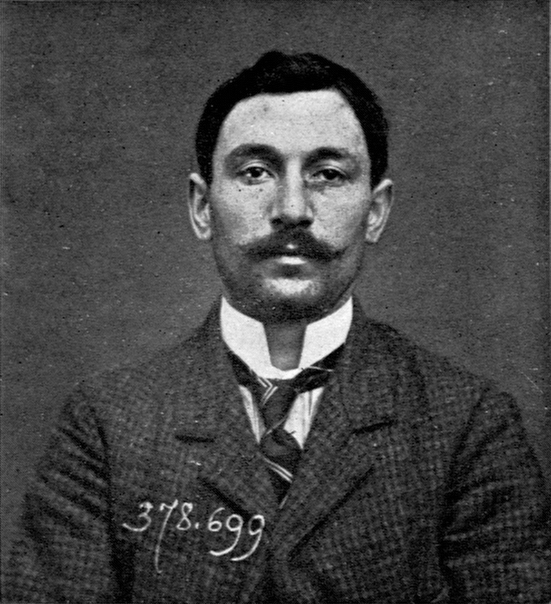 Fotografía policial en blanco y negro de un hombre joven con bigote, de frente, con la mirada fija