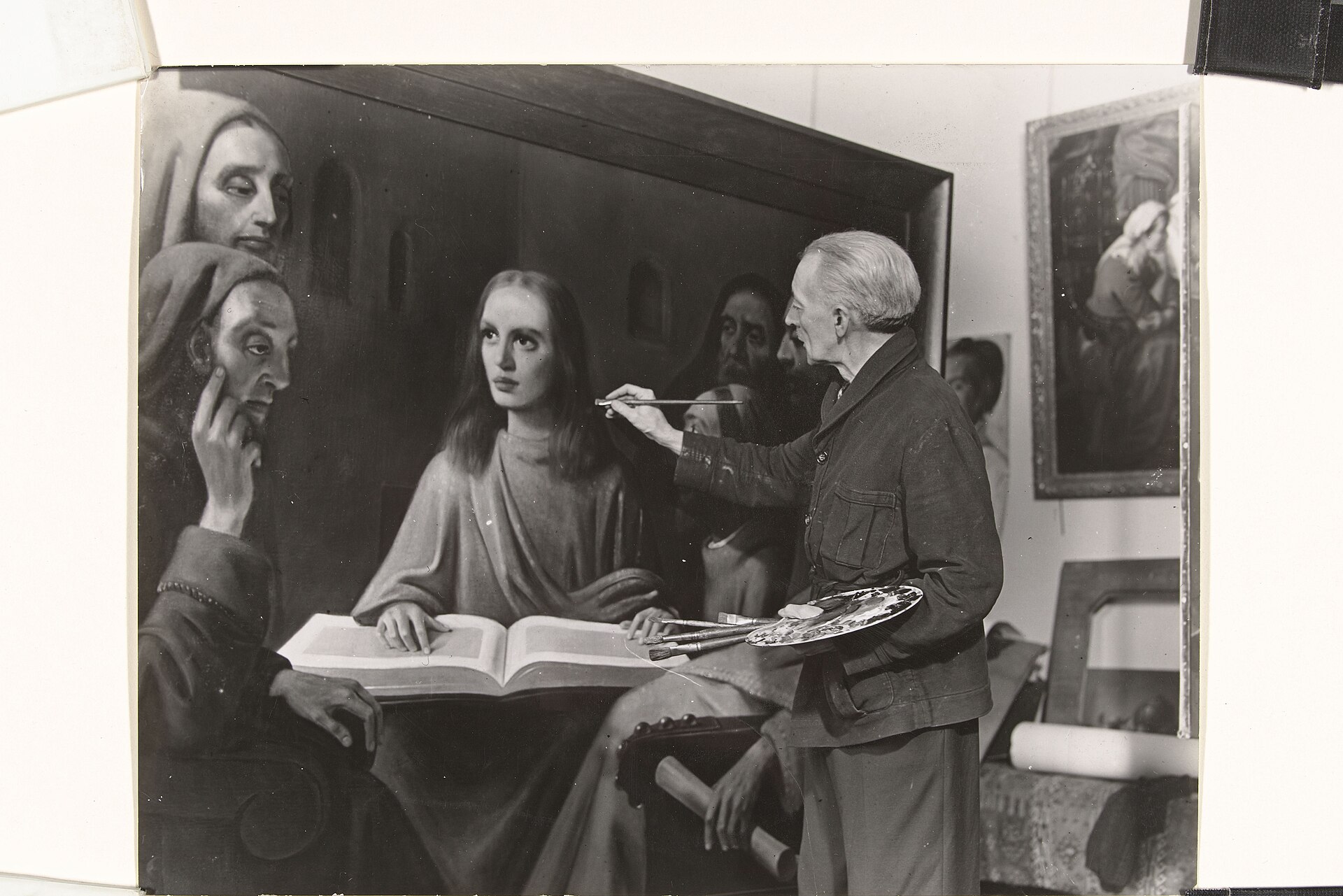 Fotografía de 1945 de Han van Meegeren pintando un cuadro grande ante un caballete, rodeado de observadores en una sala
