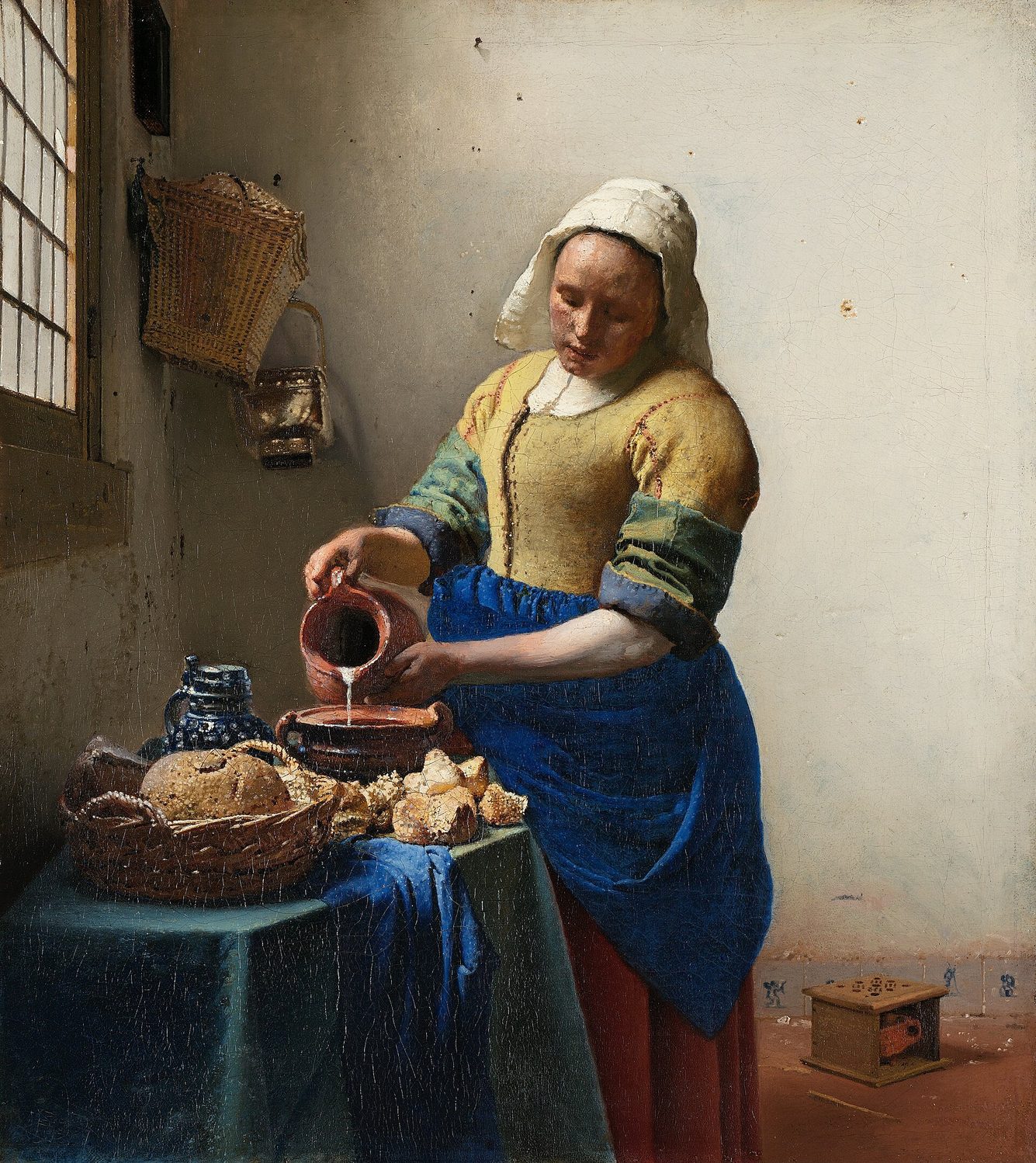 La lechera de Vermeer: una mujer junto a una mesa vierte leche de una jarra, con delantal azul intenso y corpiño amarillo