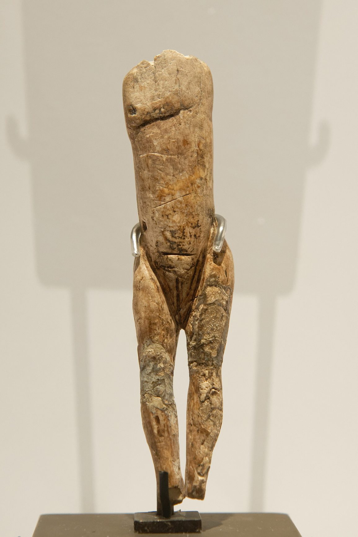 Figurilla de marfil de unos ocho centímetros sin cabeza ni brazos, con el vientre plano y la vulva marcada por una incisión, montada sobre un soporte museístico