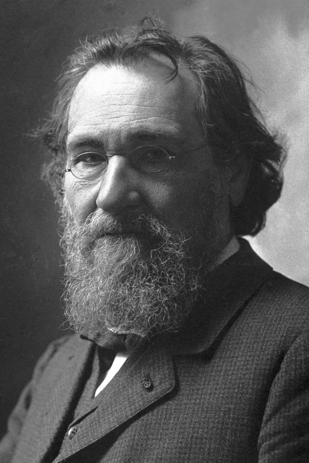Fotografía en blanco y negro de un hombre con barba y pelo largo y despeinado, con gafas