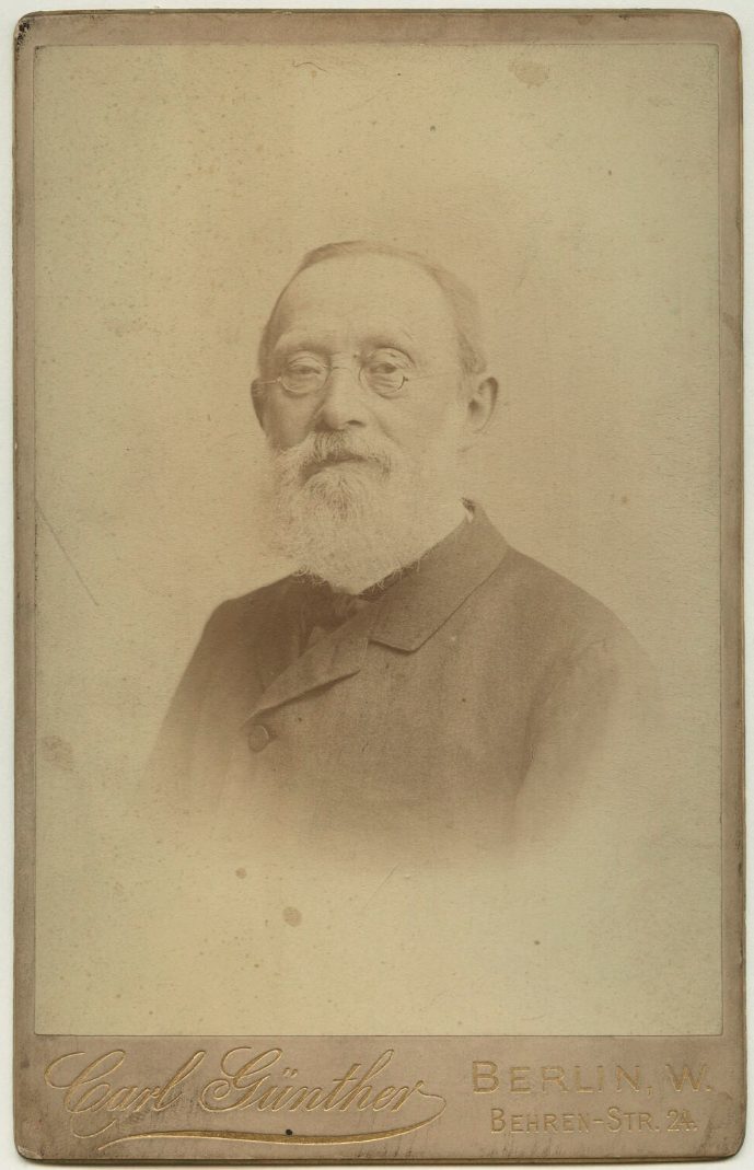Retrato fotográfico de un hombre mayor con gafas pequeñas y traje oscuro, de finales del siglo XIX