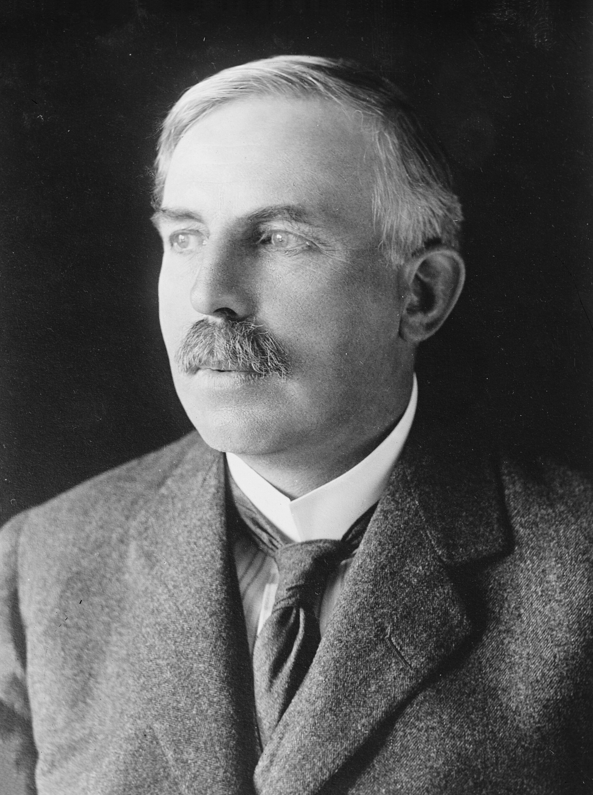 Retrato fotográfico de Ernest Rutherford, con bigote, traje y cuello alto
