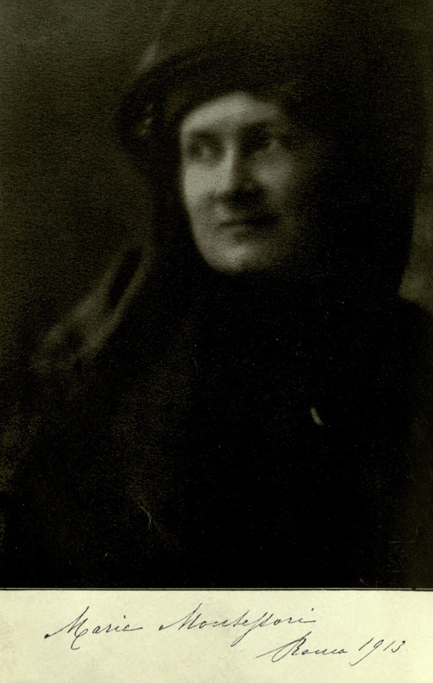 Retrato fotográfico antiguo de una mujer de mediana edad con sombrero oscuro y abrigo, mirando de frente, con una firma manuscrita en la parte inferior