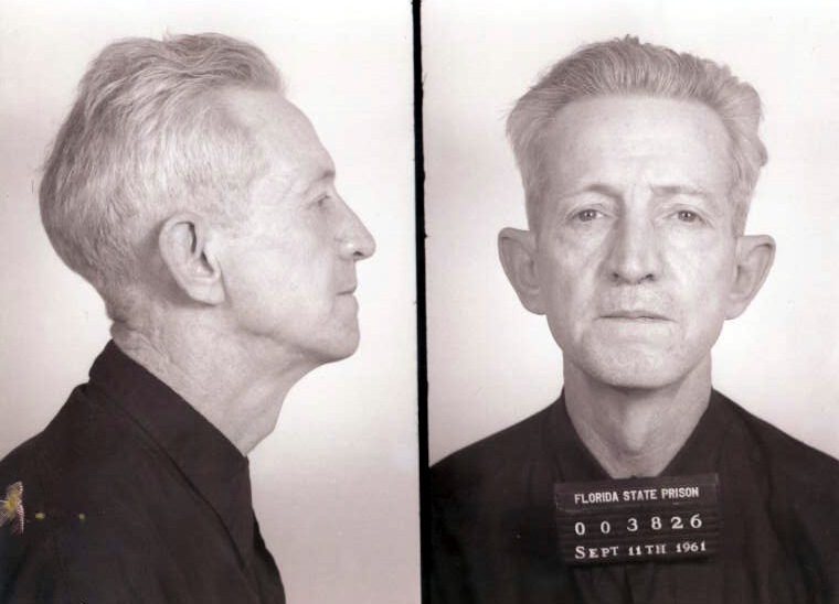 Fotografía policial en blanco y negro de un hombre de pelo canoso, de perfil a la izquierda y de frente a la derecha, con un cartel con un número y la fecha