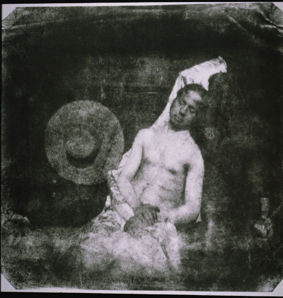 Fotografía de 1840 en la que un hombre aparece sentado y recostado, con el torso desnudo, los ojos cerrados y un sombrero de paja a su lado, simulando ser un cadáver