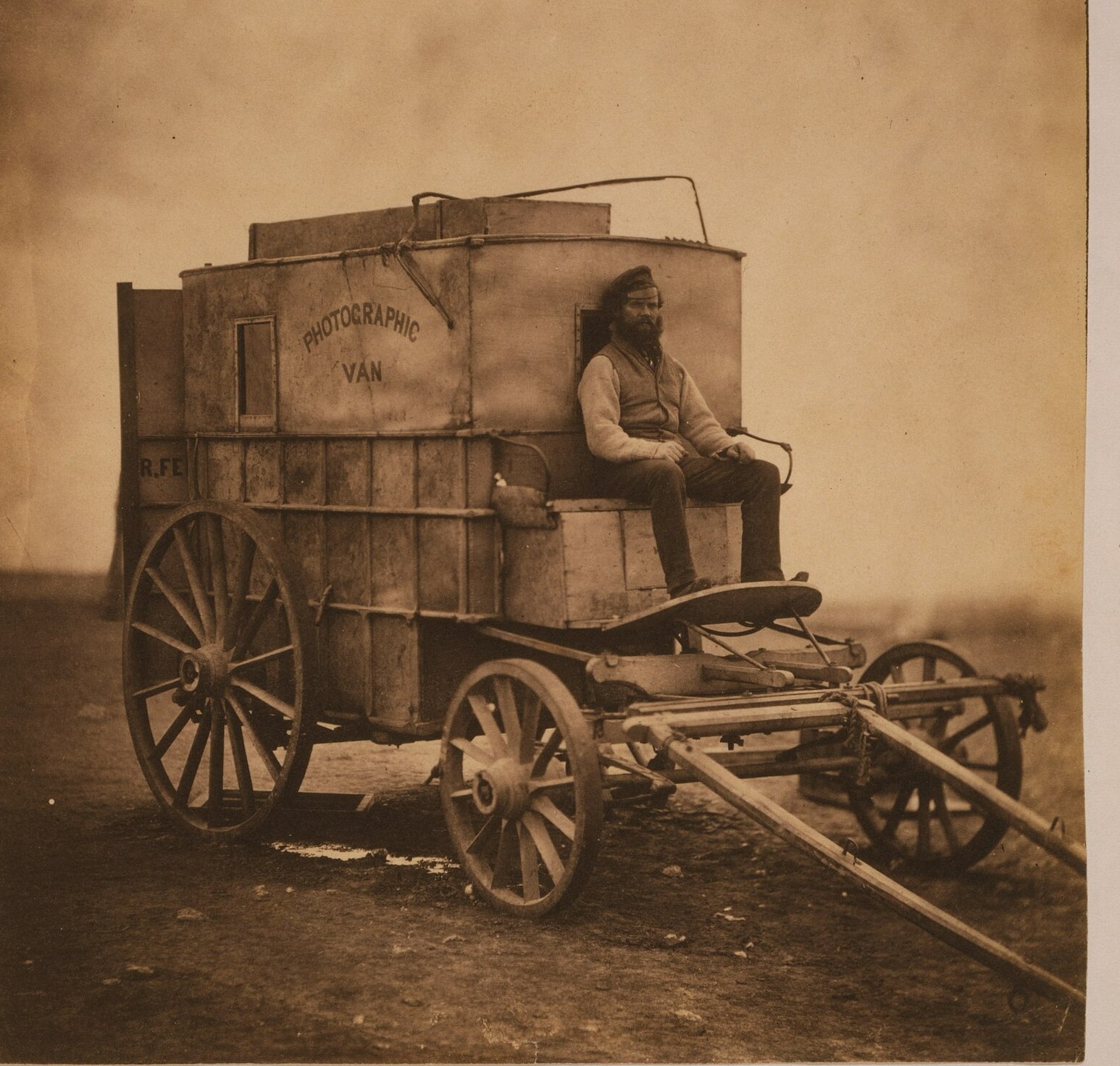Fotografía de 1855 de un carromato de madera con el rótulo «Photographic Van» y un hombre con gorro militar sentado en el pescante