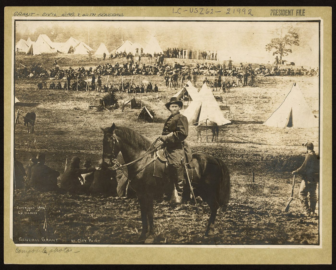 Fotografía antigua de un general a caballo en primer plano ante un campamento con tiendas blancas y un grupo numeroso de soldados al fondo
