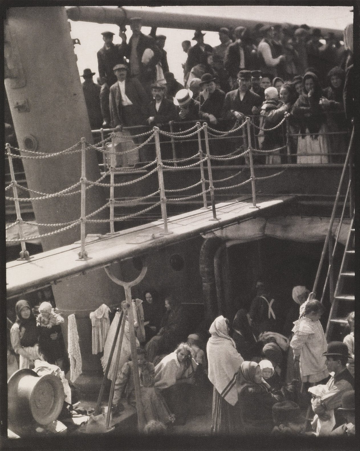 Fotografía de 1907 tomada desde una cubierta superior de un barco, con una pasarela, una escalera y dos niveles llenos de pasajeros