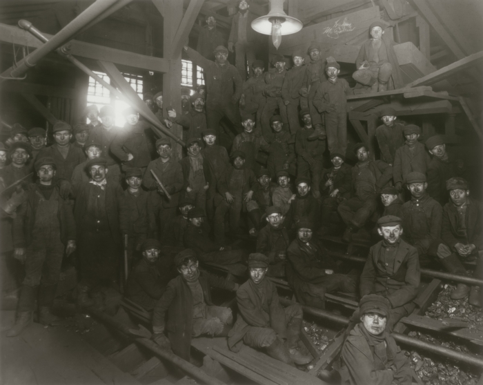 Fotografía de 1911 con decenas de niños y adolescentes cubiertos de polvo de carbón sentados en las rampas de una planta de cribado