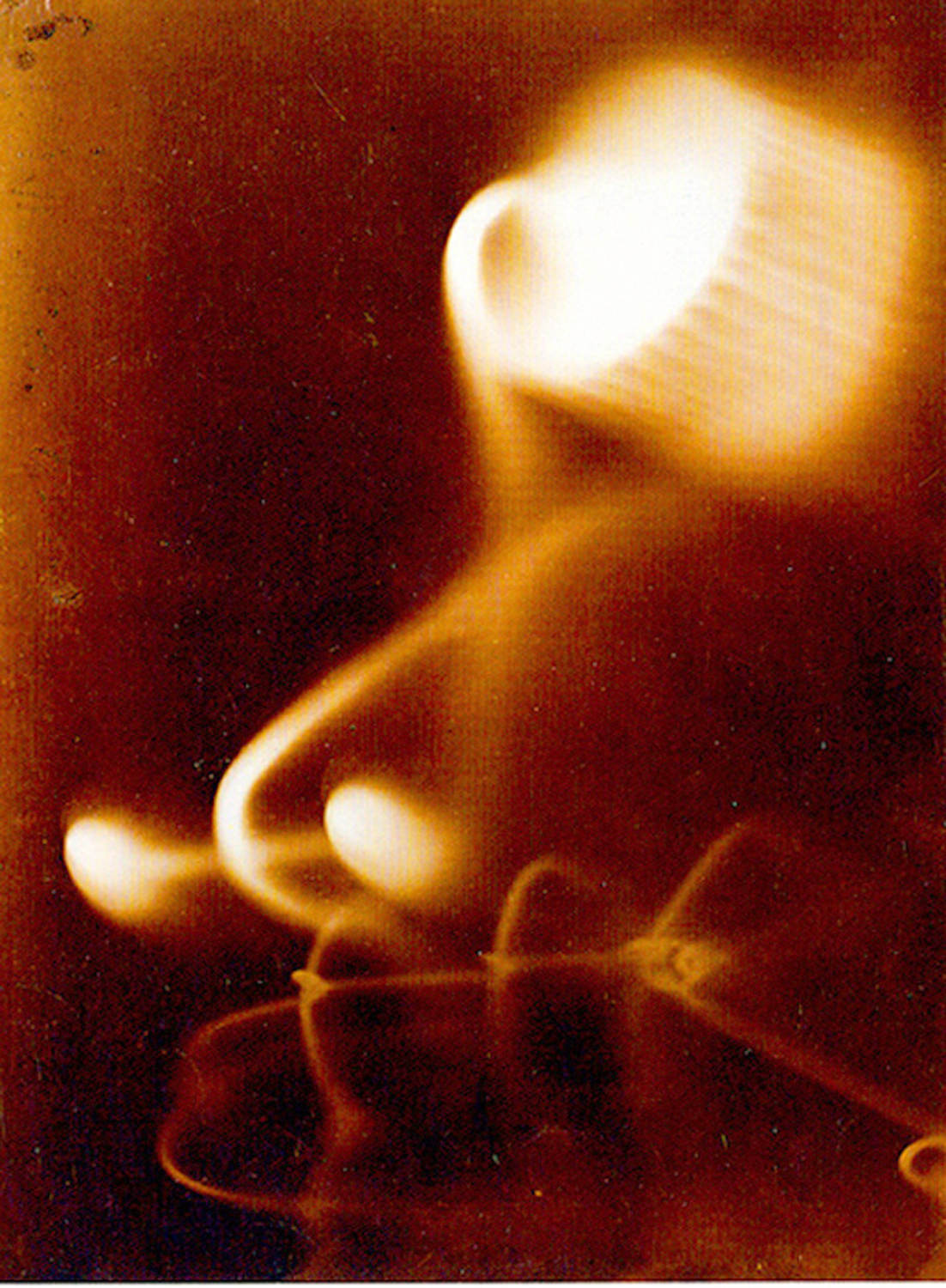 Fotograma abstracto con formas curvas luminosas y estelas claras sobre un fondo oscuro y cálido