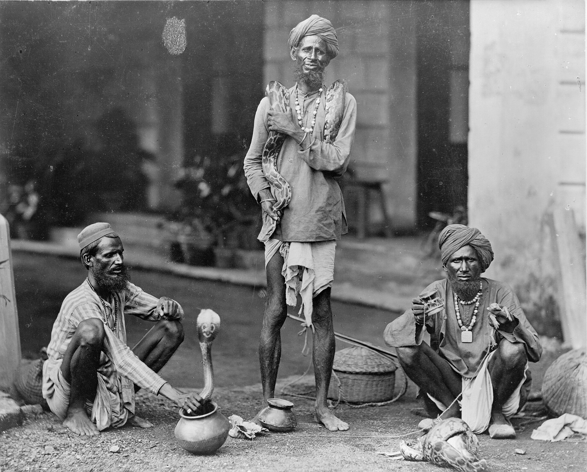 Tres encantadores de serpientes con una cobra en un cesto, India, hacia 1890-1900