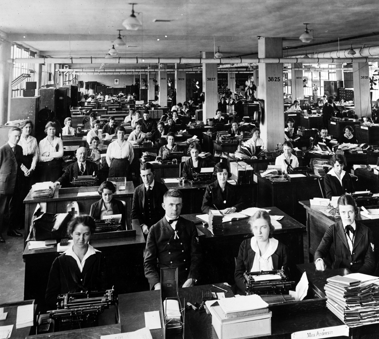 Sala de máquinas de escribir del Departamento de la Armada de Estados Unidos en 1918-1919, llena de mujeres trabajando, con dos hombres supervisando en primer plano