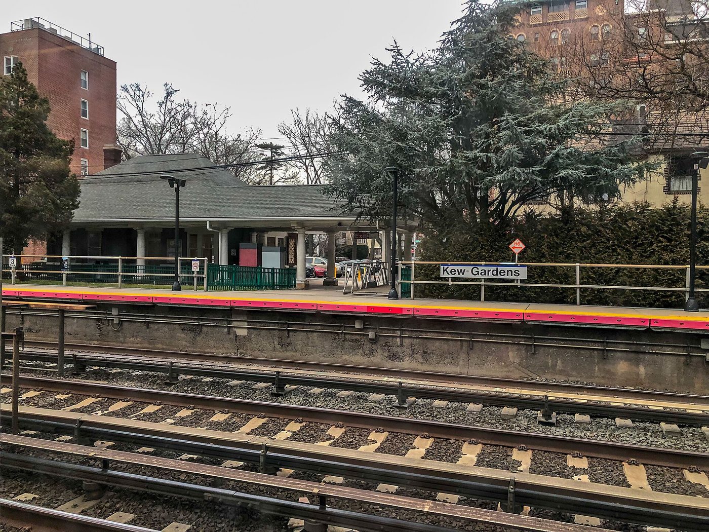 Andén de una pequeña estación de tren de cercanías con árboles detrás, visto desde un tren