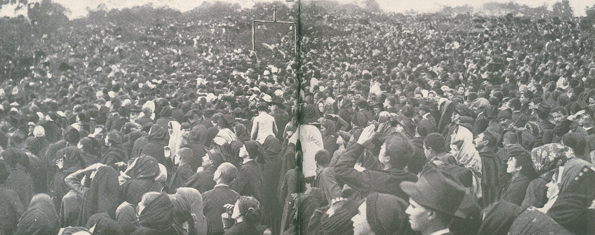 Fotografía en blanco y negro muy ancha de una multitud compacta de cabezas y sombreros que ocupa todo el encuadre