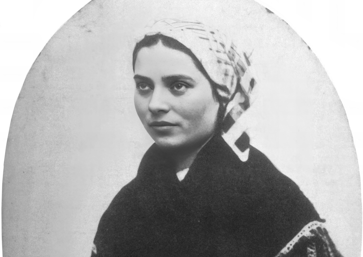 Retrato fotográfico antiguo de una joven con pañuelo blanco anudado a la cabeza y chal oscuro, mirando de lado