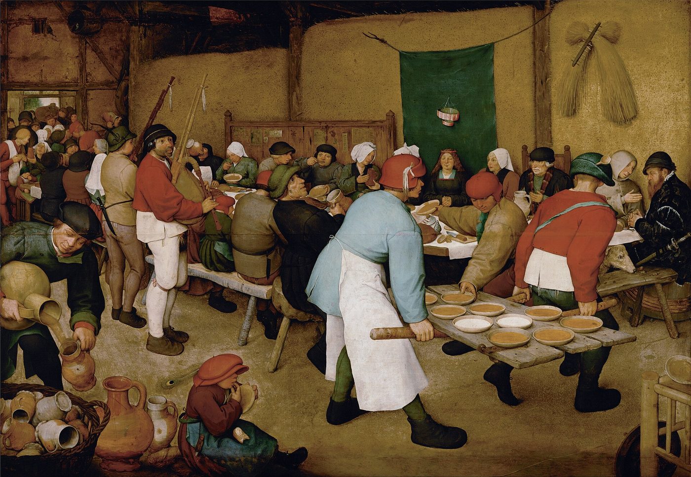 Bruegel el Viejo, «Banquete de bodas campesino»: comensales apretados en un granero comiendo gachas en platos servidos sobre una puerta
