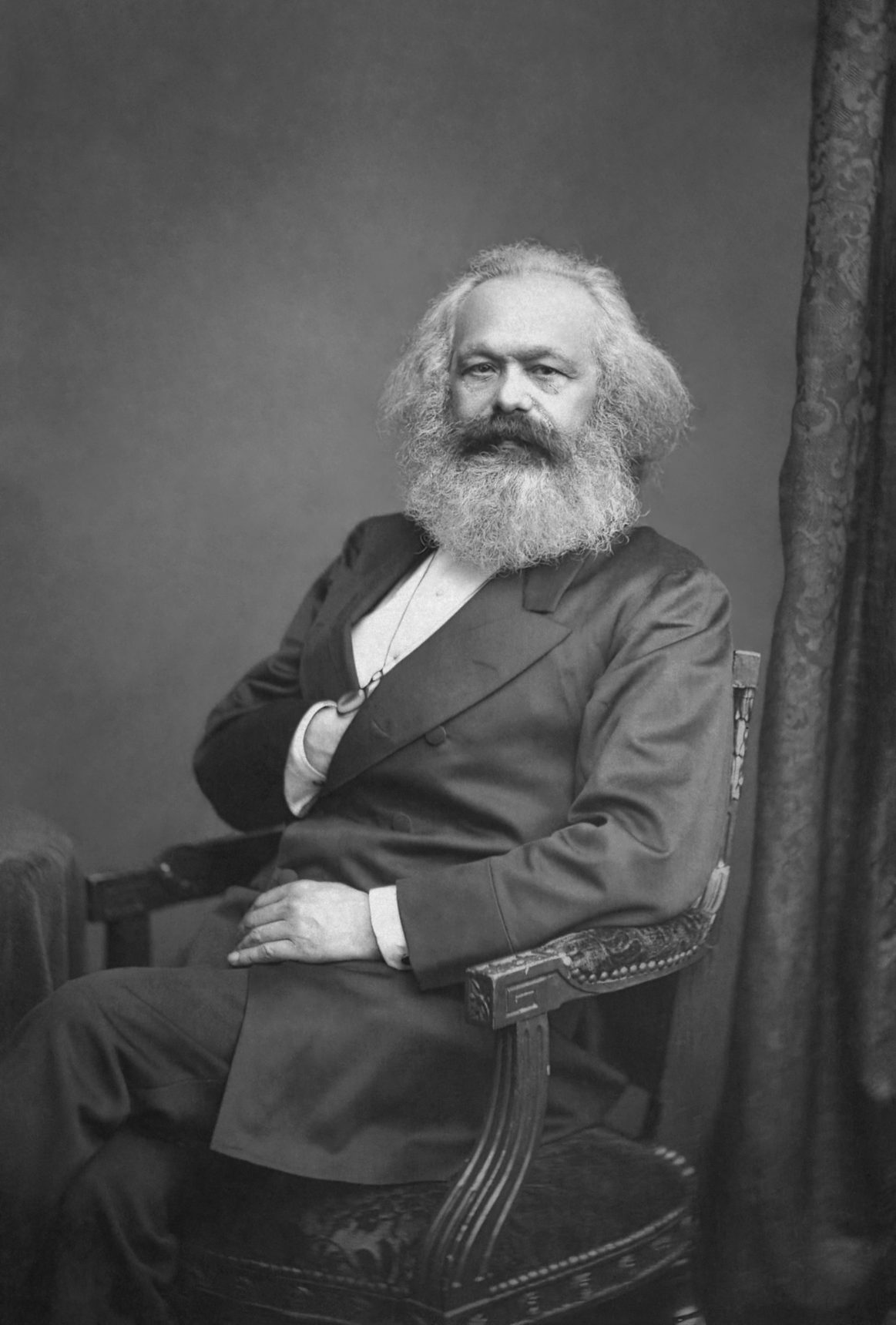 Retrato fotográfico de Karl Marx sentado, con barba y cabello blancos, hacia 1875
