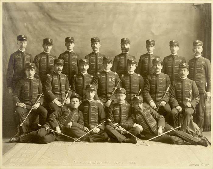 Retrato de estudio de hacia 1902 con una veintena de hombres uniformados y con espadas, dispuestos en tres filas como un equipo de exhibición