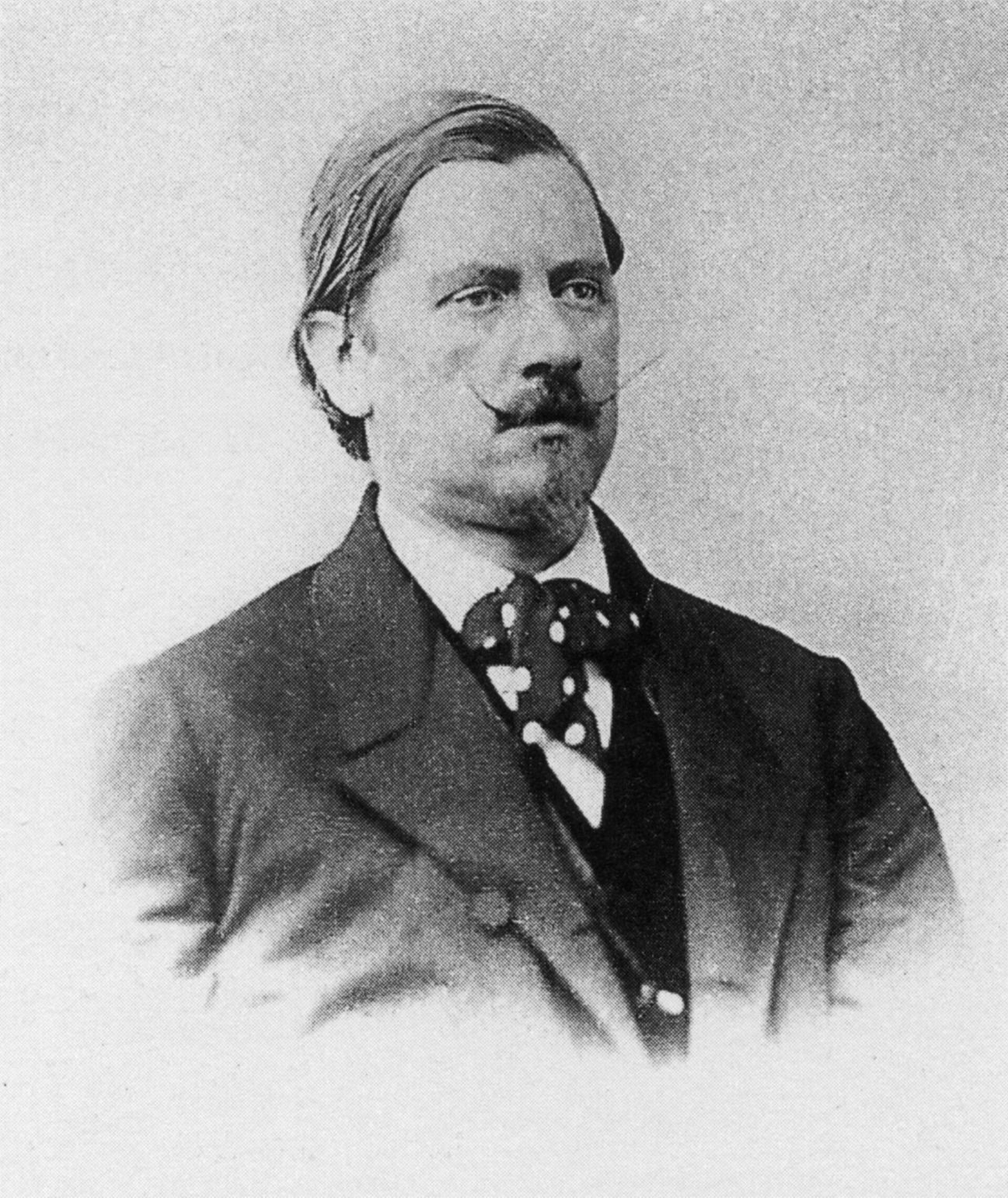 Retrato fotográfico del siglo XIX de un hombre con bigote, corbata de lazo y chaqueta oscura