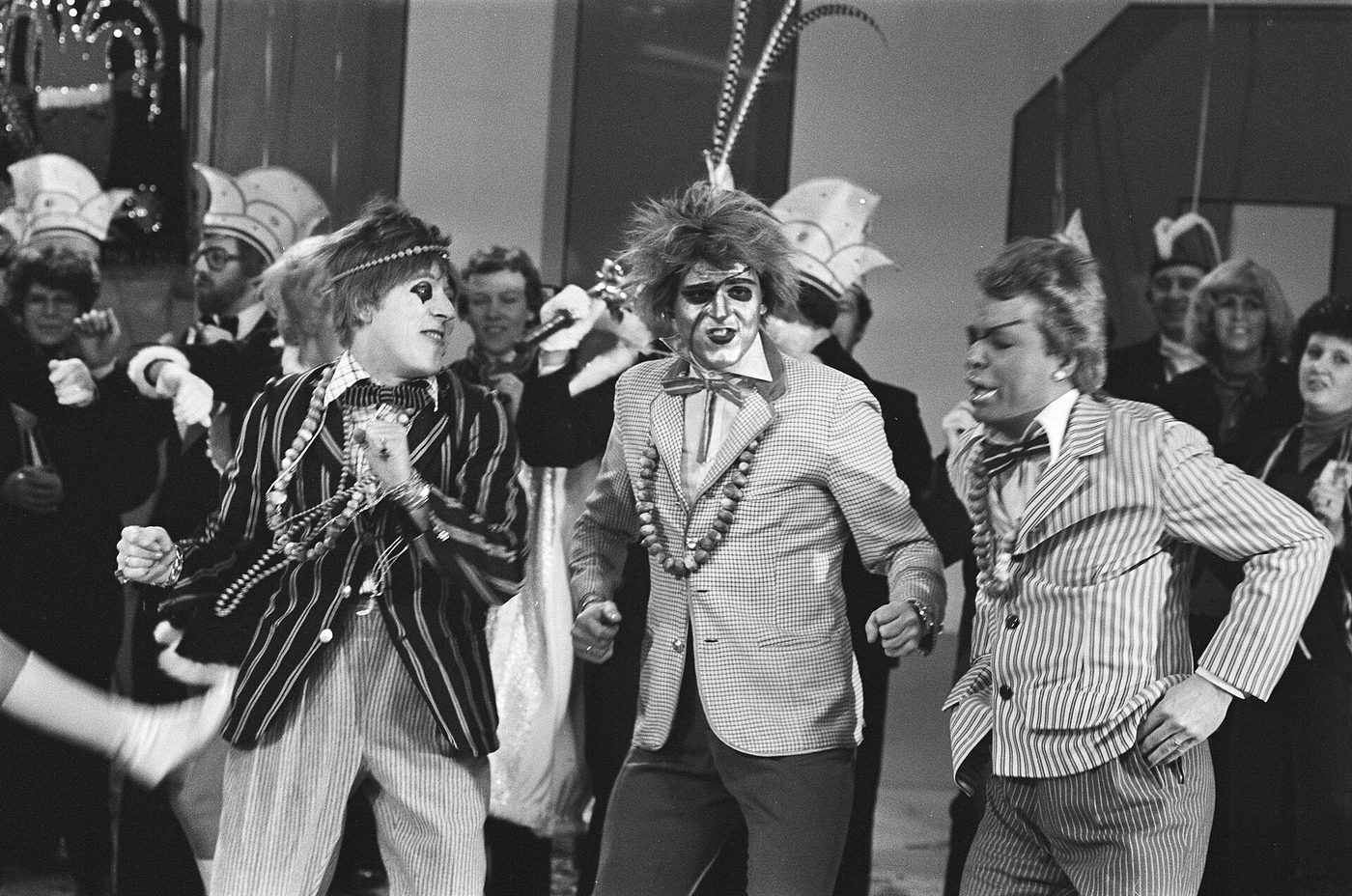Fotografía de 1978 de tres cantantes disfrazados con chaquetas de raya diplomática y maquillaje exagerado posando para televisión